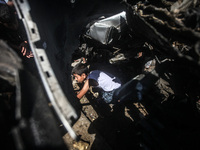 Palestinians inspect a destroyed car of two militants after Israeli airstrikes in the west of Gaza City, 27 June 2014. Two alleged militants...