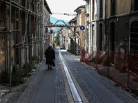 An old woman walks along the street in L'Aquila, Italy, on July 2, 2014. On the sides, damaged buildings after the quake of April 6, 2009. (