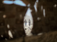 Syrian men walk amid the dust and rubble after what activists said that an Aircraft loyal to Syria's president Bashar al-Assad shelled a bar...