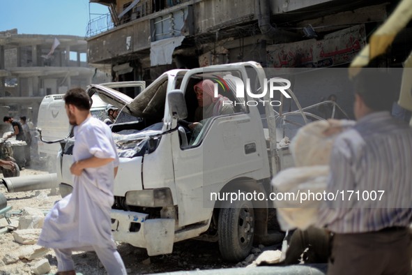 A Syrian man tries to run his car after it have been damaged because of what activists said it was a barrel-bomb by aircraft loyal to Syria'...