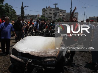 Palestinians gather around a car wreckage after an airstrike in Jabalya refugee camp in the north of the Gaza Strip, Thursday, July 10, 2014...