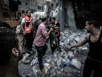 A Palestinians carry a body, a member of the Ghanam family, after being removed from under the rubble of their home following an Israeli air...