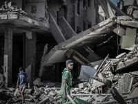 Members of the Abu Lealla family inspect the remains of their destroyed home following an airstrike in Gaza City, July 11, 2014. At least ei...