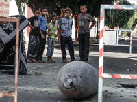 Palestinians look at the remains of a missile which witnesses said was fired by an Israeli aircraft on a street in Deir El-Balah in the cent...