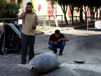 Palestinians look at the remains of a missile which witnesses said was fired by an Israeli aircraft on a street in Deir El-Balah in the cent...