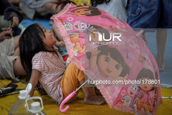 A girl plays next to an umbrella in a basketball court converted into an evacuation center in Manila, Philippines, July 16, 2014. Typhoon Ra...