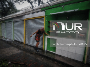 A woman rushes to save her goods inside her small stall in Manila as Typhoon Glenda, international name Rammasun, pummels through the city o...