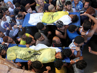 Palestinian mourners carry the bodies of two of four boys from Baker family killed in an Israeli strike, during their funeral in Gaza City o...