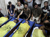 Palestinian members from Baker family mourn over the bodies of four children killed in an Israeli strike, during their funeral in Gaza City...