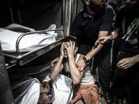 A Palestinian man cries as he holds the dead body of his young brother shortly after he got killed by an Israeli naval bombardment in the po...