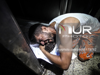 A Palestinian man cries as he holds the dead body of his young brother shortly after he got killed by an Israeli naval bombardment in the po...
