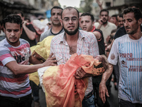 A Palestinian relative carries the body of a kid during the funeral of eight members of Abu Jarad family who were killed overnight in an Isr...