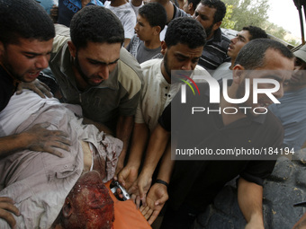 Rescue workers carry the body of a member of al-Shair family, after removing it from under the rubble of their home following an Israeli air...