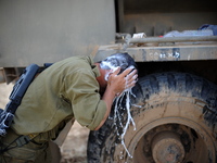 UNSPECIFIED, ISRAEL - JULY 19, 2014: An Israeli soldier is washing his head in an army deployment area near Israel's border with the Gaza St...
