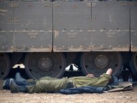 UNSPECIFIED, ISRAEL - JULY 19, 2014: An Israeli soldier sleeps next to an APC in an army deployment area near Israel's border with the Gaza...