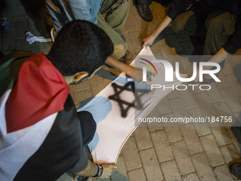 Boys make an Israeli flag out of a ripped t-shirt and spray paint in order to burn it in from of the Israeli consulate. Thousands of people...
