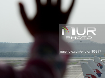 An unidentified child's hand is silhouetted as she leans on the window to see Malaysia Airlines planes taxied on the tarmac of Kuala Lumpur...