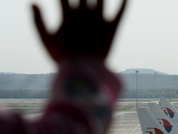 An unidentified child's hand is silhouetted as she leans on the window to see Malaysia Airlines planes taxied on the tarmac of Kuala Lumpur...