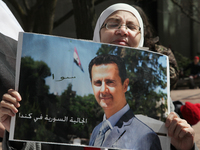 Syrian woman holds a poster of Syrian President Bashar al-Assad during a protest against US President Donald Trump's decision to launch airs...