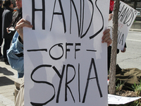 Demonstrator holds a sign saying 'Hands Off Syria' during a protest against US President Donald Trump's decision to launch airstrikes agains...