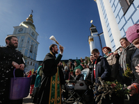 A priest sprinkles faithful and their willow bunches with a Holy Water near the church as eastern Christians hold Palm Sunday feast in Kyiv,...
