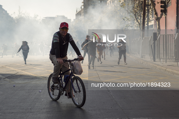 Protesters and passers-by flee tear gas thrown by anti-riot police.
Thousands of students marched through the main avenue of Santiago, on A...