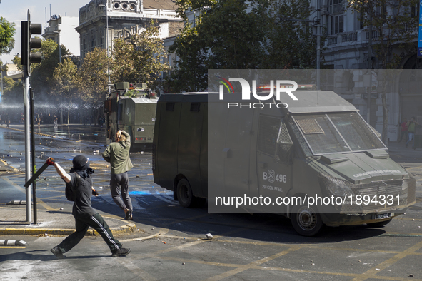 A protester throws an object at a police car.
Thousands of students marched through the main avenue of Santiago, on April 11, 2017, demandi...