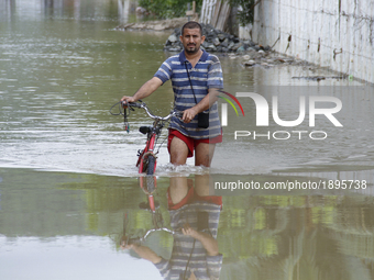 A men is transported on his bicycle through water-covered streets as a result of the heavy rains that have flooded several sectors of Manabí...