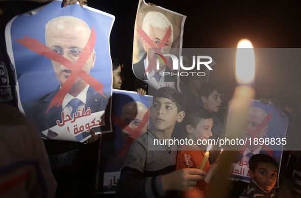  Palestinian boy holds a candle and a crossed poster depicting Prime Minister Rami Hamdallah and  a portrait of Palestinian leader Mahmud Ab...
