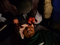A Kashmiri Protestor with blood soked hands sits  next to the body of  Shabir Ahmed, a teenage boy During his funeral prayers  in Srinagar,...