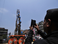 A Man takes pictures as Devotees arranging piles of wood for making the chariot of Idol Rato Machindranath 'Rain of God' at Pulchowk, Laltip...