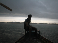 A Bangladeshi boatman navigating his boat on a river black could behind him due to raining at Bisanakandi in Sylhet, Bangladesh near Meghala...