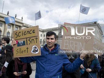 A man attending the 'March for Science' holds banners reading 'science isn't silence' and 'feed your brain' in Berlin, Germany on April 22,...