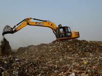 An indian Man dumps wastages through a heavy waste handling machine , in a huge Garbage dump yard ,  on World Earth Day , in Allahabad on Ap...