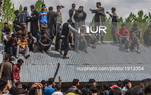Kashmiri Muslim look from the roof top of a building towards the body being carried  of   Younis Maqbool Ganie, a pro Kashmir rebel killed i...