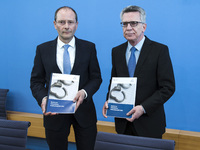 German Interior Minister Thomas de Maiziere (R) and Saxony's Interior Minister Markus Ulbig (L) hold a copy of the Police Criminal Statistic...