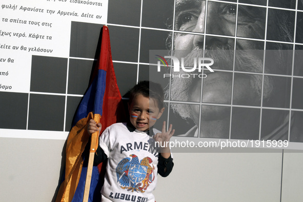 A boy with the Armenian flag in front of a photograph of the American Armenian novelist William Saroyan, at Syntagma square, in central Athe...