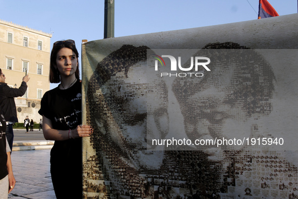 A woman holds a banner with photos of victims of the Armenian Genocide in front the Greek Parliament, in Athens, on Monday April 24, 2017. H...