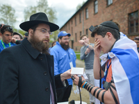 A young man prays with tefillin inside the former German Nazi Death Camp Auschwitz-Birkenau during the annual March of the Living. 
Jewish p...