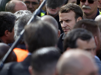 French presidential election candidate for the En Marche ! movement Emmanuel Macron (C) talks to an employee as he arrives at the Whirlpool...