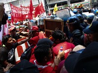 Workers and protesters scuffle with policemen as they attempt to reach the vicinity of the US Embassy during a rally in Manila, Philippines...