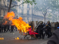 Protesters push a burning trolley towards French CRS anti-riot police officers during a march for the annual May Day workers' rally in Paris...