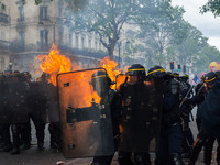French CRS anti-riot police officers are engulfed in flames as they face protesters during a march for the annual May Day workers' rally in...