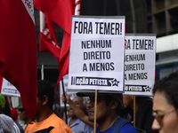 A demonstrator holds up a sign that reads 'Out Temer' during a workers union protest against President Michel Temer's government on Labor Da...