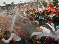 Quezon City, Philippines - Militant groups take cover as they are hosed by water canons during the President's State of the Nation Address (...