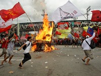 Quezon City, Philippines - Militant groups run around a burning effigy of President Benigno Aquino III during the President's State of the N...
