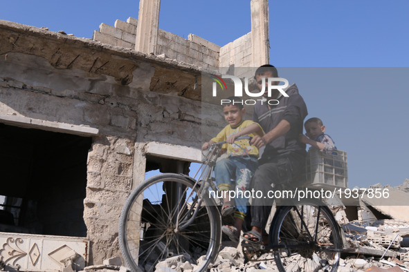 A Syrian man rides a bike carryin his children past  destroyed buildings in the rebel-held town of Douma, on the eastern outskirts of the Sy...
