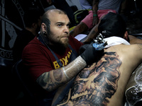 An artist works on a man during Athens International Tatoo Convention, at the Olympic Tae Kwon Do Centre, on Saturday May 13, 2017. The visi...