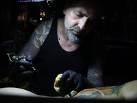 An artist works on a man during the Athens International Tatoo Convention, at the Olympic Tae Kwon Do Centre, on Saturday May 13, 2017. The...