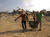 Palestinian rescue workers carry the body of a member of Duheir family, after removing it from under the rubble of a building destroyed by a...